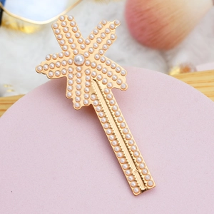 Detailed view of a gold hair clip with white pearls arranged in a star pattern