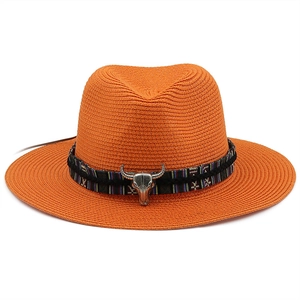 Detail of vibrant orange straw hat featuring an ethnic woven band and silver bull skull charm