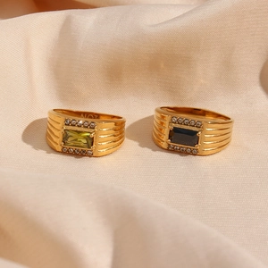 Detail of 18K gold-plated rings with green and black rectangular zircon on silk fabric