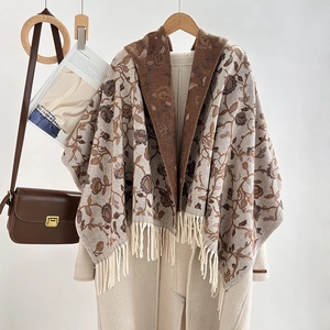 Ethnic jacquard tassel shawl in brown and beige floral pattern over a beige coat