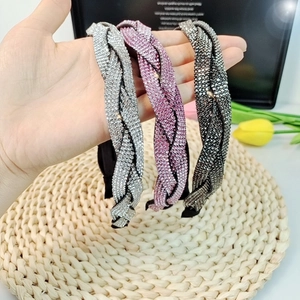 Detailed view of three braided rhinestone headbands in silver, pink, and dark grey tones