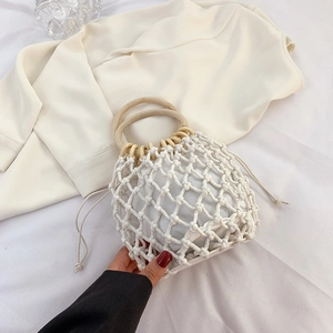 Detail of hand-woven mesh bag featuring a round wooden handle and drawstring inner pouch