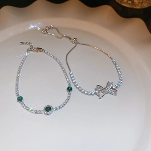 Close-up of zircon bow bracelet and green stone bangle in a white ceramic dish