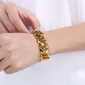 Close-up of a chunky golden stainless steel Cuban link bracelet worn by a male model