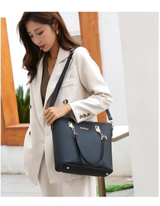 Detail of a black faux leather tote bag with gold hardware on a professional model
