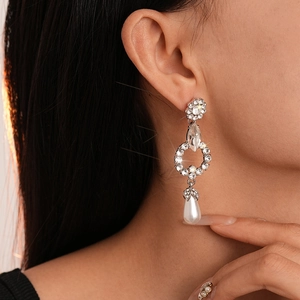 Close-up of sparkling floral geometric earrings with rhinestones and drop pearls on a model