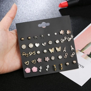 Detailed set of 30 pairs of vintage floral and bow stud earrings on a black display card
