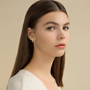 Detailed close-up of a model wearing elegant gold bow earrings for fashion display