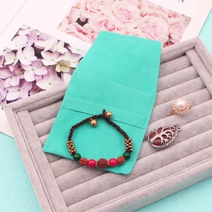 Close-up of mint green suede jewelry pouch with pearl ring and woven bracelet