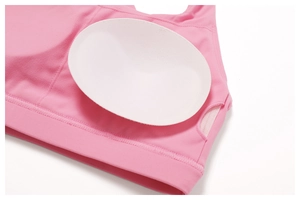 Detail showing removable white pads and breathable mesh pockets on pink sports bra