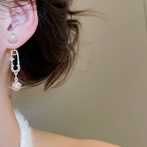 Macro des boucles d'oreilles en argent avec pendentif planète et perle rose