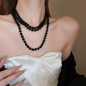 Close-up of layered black resin pearl necklace on model with elegant drape effect