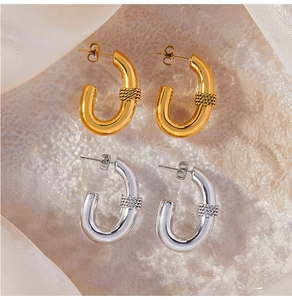 Macro detail of U-shaped gold and silver earrings with braided texture on silk