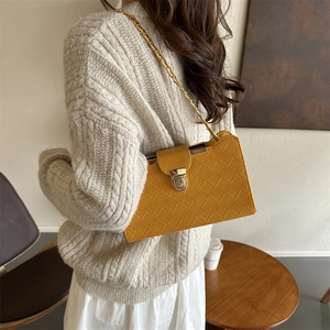 Chic mustard yellow quilted baguette bag with gold chain strap worn by model