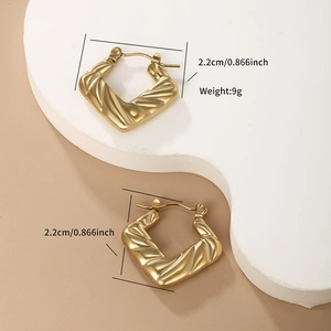 Detail view of 22mm golden square hoop earrings with wavy textured metallic surface