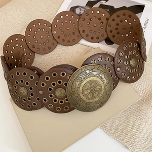 Macro view of vintage brown leather chain belt with metal rivets and floral buckle