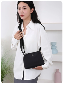Mini sac à bandoulière en nylon noir porté par un mannequin dans un cadre minimaliste