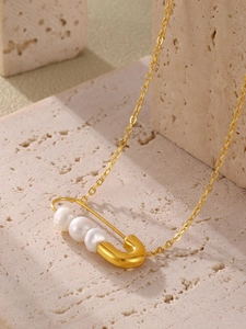 Détail du pendentif épingle à nourrice doré avec trois perles sur pierre naturelle