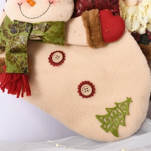 Detail of beige felt Christmas stocking with plush snowman and green scarf