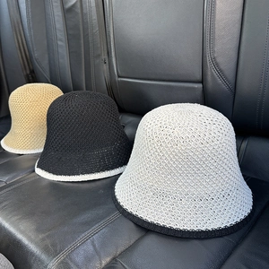 Detailed view of hollow knit bucket hats in beige, black and white on leather seat