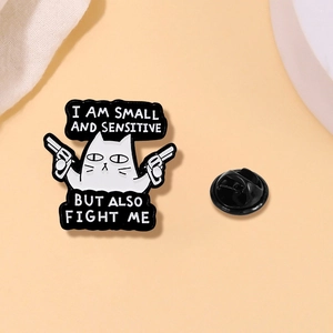 Detail of cartoon cat enamel pin with black rubber back and funny quote text