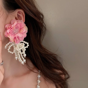 Pink floral stud earrings with white faux pearl tassels on model for vintage elegant look