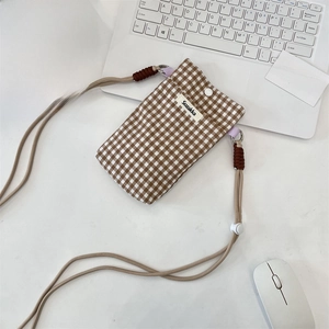 Detail of checkered fabric phone pouch with snap button and adjustable crossbody strap