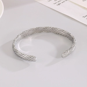 Detailed macro view of silver stainless steel C-shape cuff bracelet with spiral texture