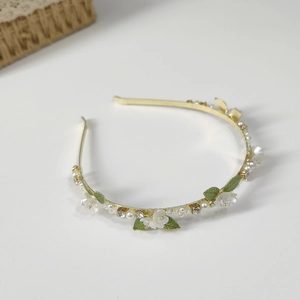 Detail of gold floral headband with white pearls, green enamel leaves and rhinestones