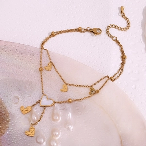 Detailed macro view of 18K gold double-layer anklet with white shell heart and beads