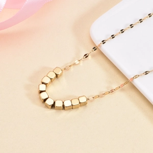 Golden titanium steel necklace with square beads on white display tray with pink ribbon