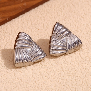 Close-up of textured silver triangle stud earrings on minimalist neutral background