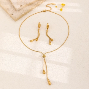 Detailed flat lay of golden stainless steel teardrop jewelry set on marble background