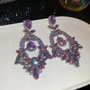 Close-up of vintage teardrop earrings with purple and pink crystals on white plate