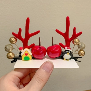Close-up of Christmas hair clips featuring red antlers, gingerbread house and penguin charms