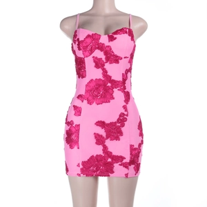 Détail de la robe moulante rose avec broderie florale rouge et coupe ajustée