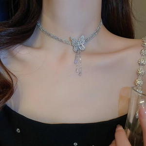 Détail du collier argenté multicouche avec pendentif papillon en zircon et franges