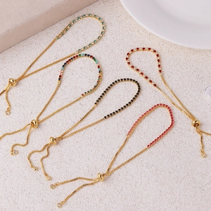 Details von verstellbaren Gold-Tennisarmbändern mit bunten Zirkonia auf Steinuntergrund