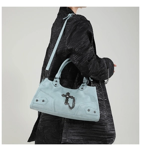 Detailansicht der hellblauen Tasche mit schwarzer Kreuzkette auf einem schwarzen Mantel