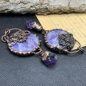 Detailed shot of bronze lion head earrings with round purple crystals and raw stone drops