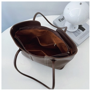 Top view of large brown tote bag interior showing multiple zip compartments and storage space