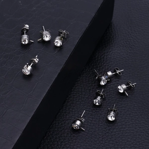 Macro shot of silver stainless steel crystal stud earrings on a textured black background