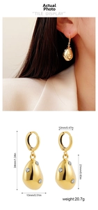 Detail showing irregular gold teardrop earrings with zircon and precise dimensions