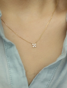 Macro shot of clover pendant with pavé set white crystals on a gold chain