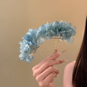 Detailed view of light blue fabric flower hair pin with golden double prongs for styling