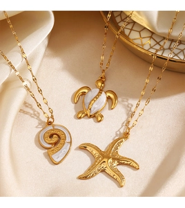 Detailed view of three gold necklaces with turtle, conch, and starfish charms on silk