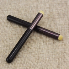 Detail of round head concealer lip brushes with black handles and sponge tips on beige fabric