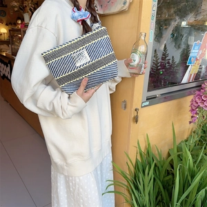 Detail of hand-held colorful striped woven toiletry bag with Bozakka label and geometric patterns