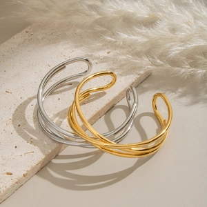 Minimalist layered wrap open bangles in gold and silver finish on a textured stone base