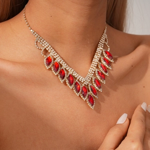 Detail of V-shaped gold necklace featuring teardrop red gemstones and diamond tassels